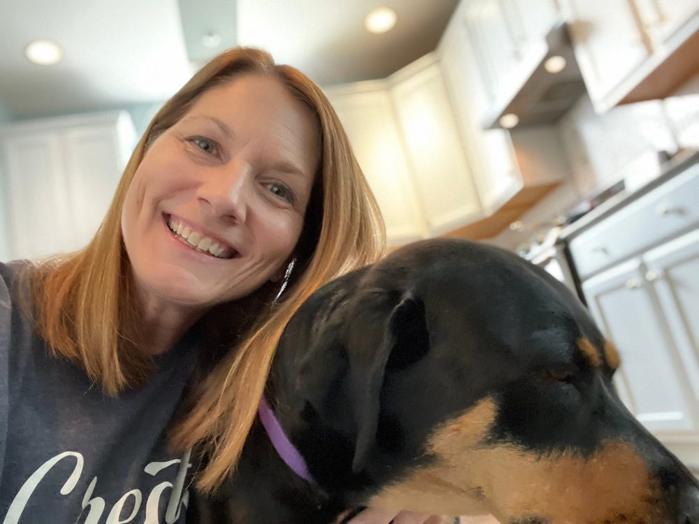 Stephanie smiling with her dog in the kitchen